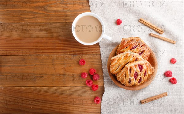 Puff pastry buns with strawberry jam on wooden background with linen textile and a cup of coffee. top view, flat lay, copy space