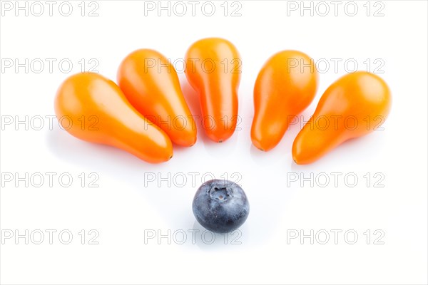 Five small ripe orange grape tomatoes and a single blueberry isolated on white background. top view, close up. contrast and diversity concept