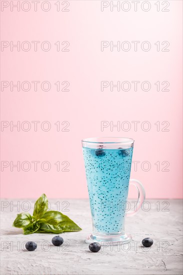 Glass of blueberry blue colored drink with basil seeds on a gray and pink background. Morninig, spring, healthy drink concept. Side view, copy space