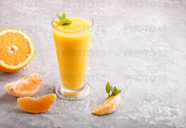 Glass of orange juice on a gray concrete background. Morninig, spring, healthy drink concept. Side view, copy space