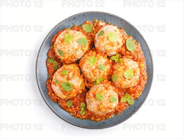 Pork meatballs with tomato sauce, oregano leaves, spices and herbs on blue ceramic plate isolated on white background. top view, close up