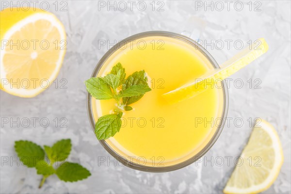 Glass of lemon drink on a gray concrete background. Morninig, spring, healthy drink concept. Top view, close up, flat lay