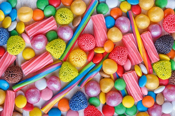 Mixed multicolored candies on white wooden background. top view, flat lay