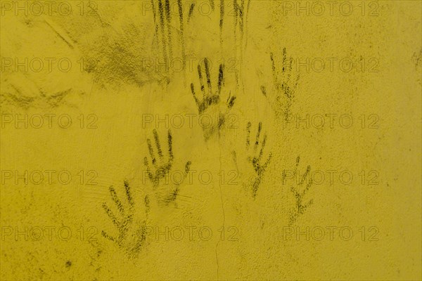 Black hand prints on side of cracked yellow wall in South Korea