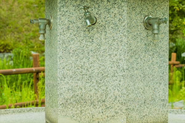 Large hand washing water fountain in a public park with lush green foliage in South Korea