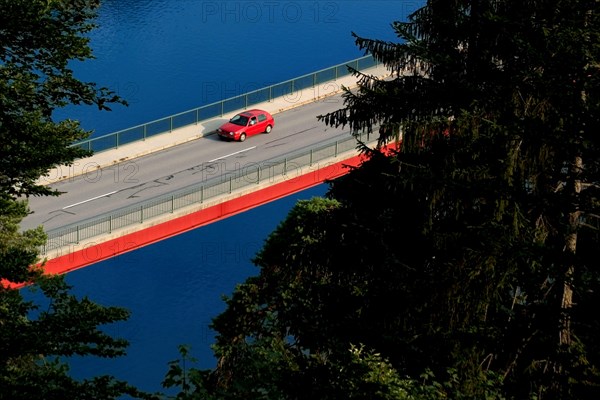 Bridge and red volkswagen car over Sylvenstein Stausee near village Fall, Bavaria, Germany, Europe