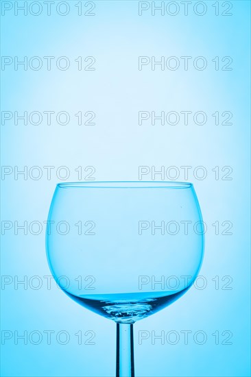 Empty wine glass against a plain blue background