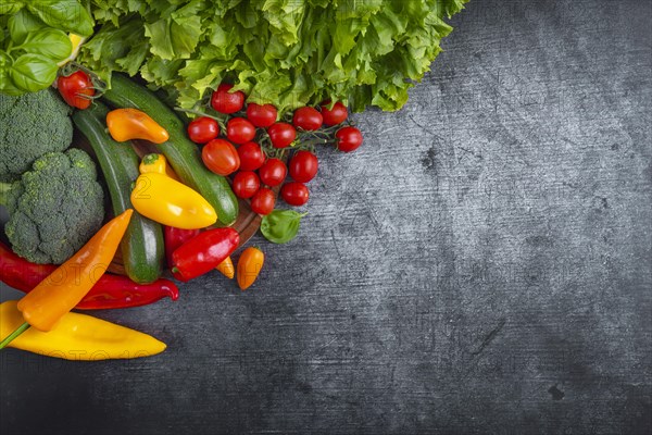 Fresh lettuce, courgettes, broccoli, tomatoes and peppers arranged on a wooden board symbolises health