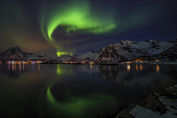 Polarlichter ueber einem winterlichen Fjord auf den Lofoten mit verschneiten Bergen und einer tollen Spiegelung im Wasser