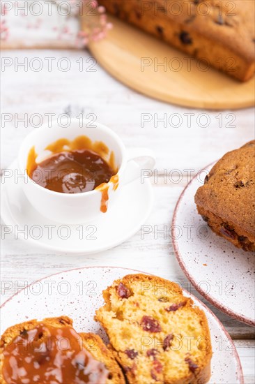 Homemade cake with raisins, almonds, soft caramel and a cup of coffee on a white wooden background. Side view, close up, selective focus