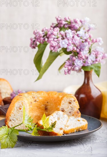 Cakes with raisins and chocolate and a cup of coffee. lilac flowers on a gray concrete background, side view