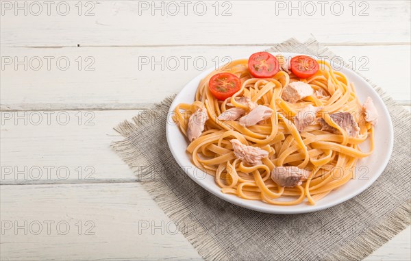 Semolina pasta with salmon on a white wooden background and linen textile. Side view, copy space