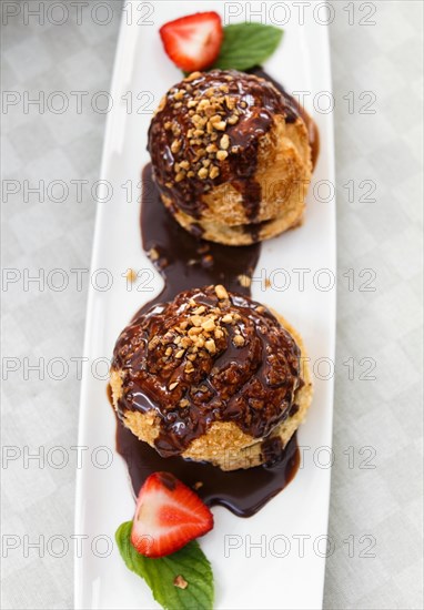 Fresh profiteroles with ice cream and chocolate on a white plate. selective focus. horizontal. top view