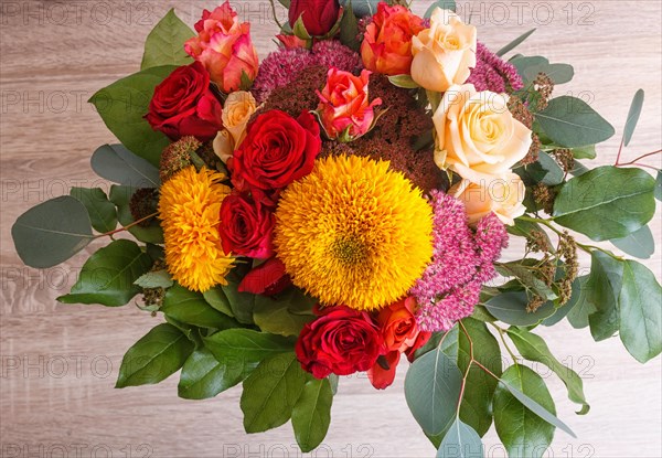 Bouquet of sunflowers and roses on a wooden background. floristic composition