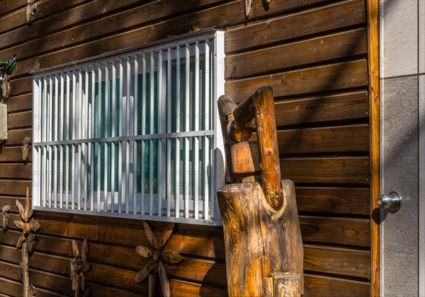 Figure of man carved from wood standing next to barred windows in wooden building located in public park on mountain in Gangwon county South Korea