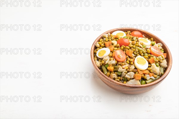 Mung bean porridge with quail eggs, tomatoes and microgreen sprouts on a white wooden background. Side view, close up, copy space