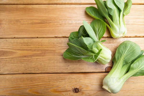 Fresh green bok choy or pac choi chinese cabbage on a brown wooden background. Top view, copy space, flat lay