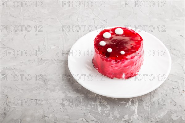 Red cake with souffle cream on a gray concrete background. side view, copy space