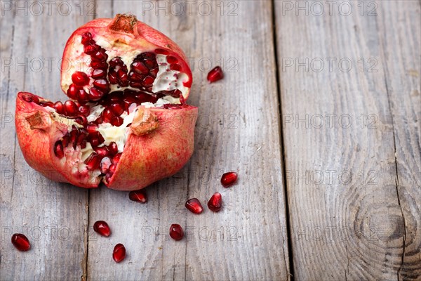 Opened ripe garnet with seeds on a rustic wooden background