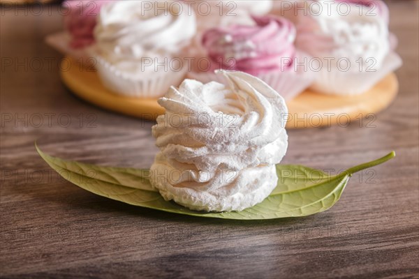 Pink and white homemade marshmallows (zephyr) on a round wooden board on a gray wooden background