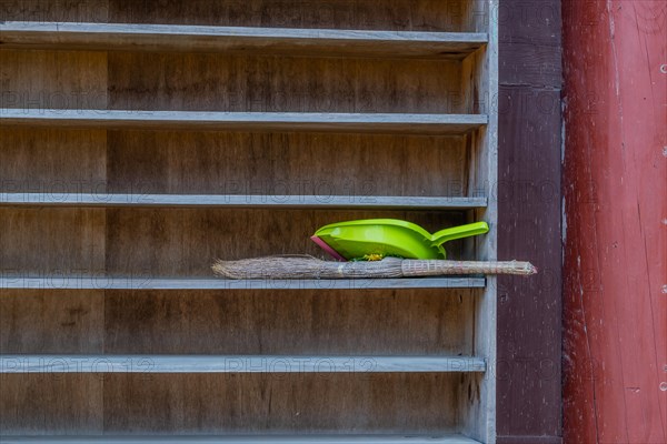 Straw hand broom and green plastic dust pan on outdoor shelve in South Korea