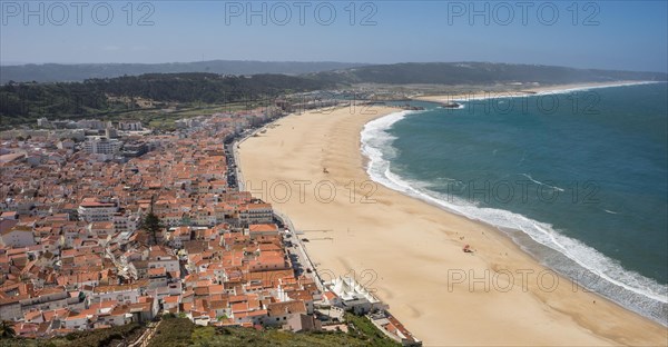 Panoramic view of a coastal town with a wide sandy beach and blue sea under a sunny sky Nazareh Portugal