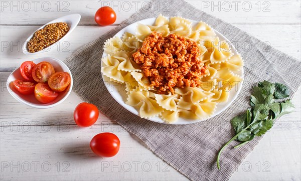 Farfalle bolognese pasta with minced meat on white wooden background. close up