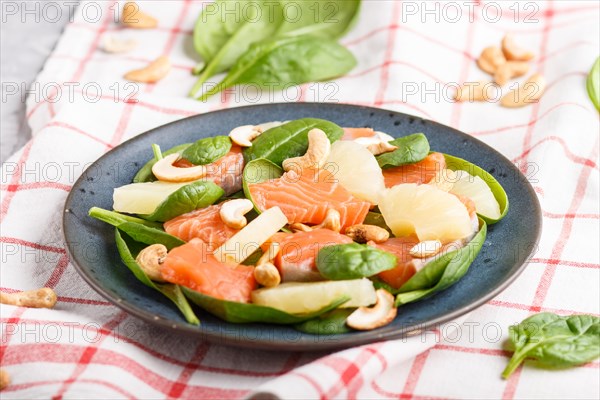 Fresh salmon with pineapple, spinach and cashew on a gray concrete background. Side view, close up, selective focus, linen tablecloth