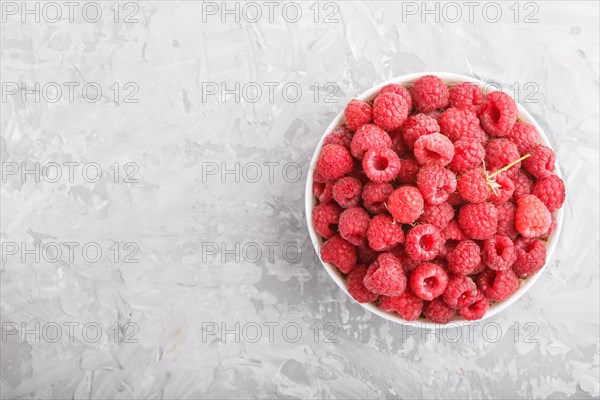 Fresh raspberry in white bowl on gray concrete background. top view, flat lay, copy space