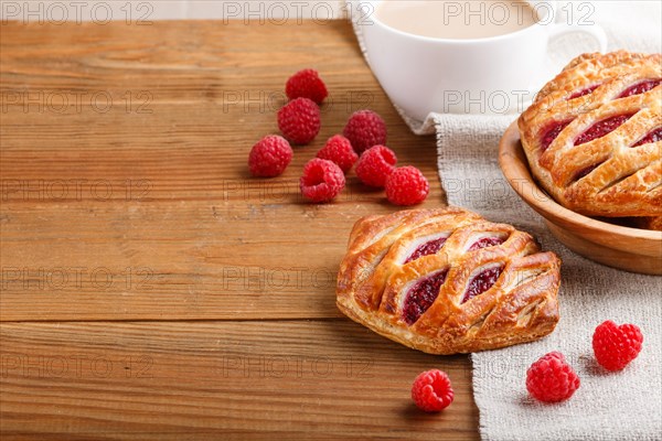 Puff pastry buns with strawberry jam on wooden background with linen textile and a cup of coffee. side view, close up, copy space