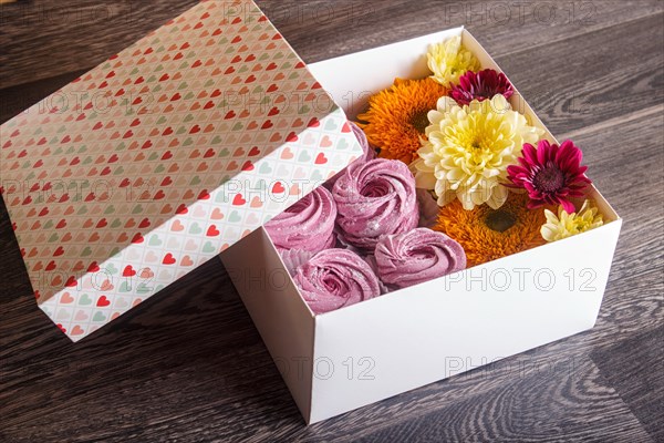 White box with pink homemade zephyr and sunflowers and chrysanthemums on gray wooden background