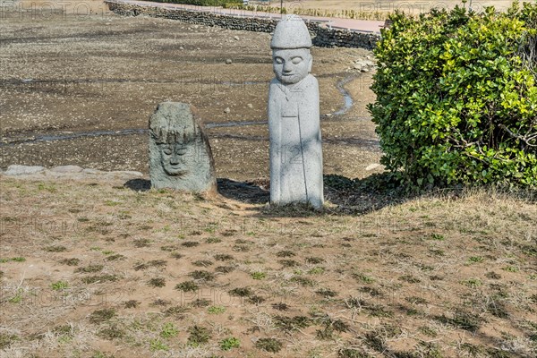 Two stone carved figures on grassy hillside in nature park in South Korea