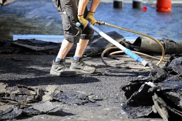 Roofers remove old bitumen and roof waterproofing