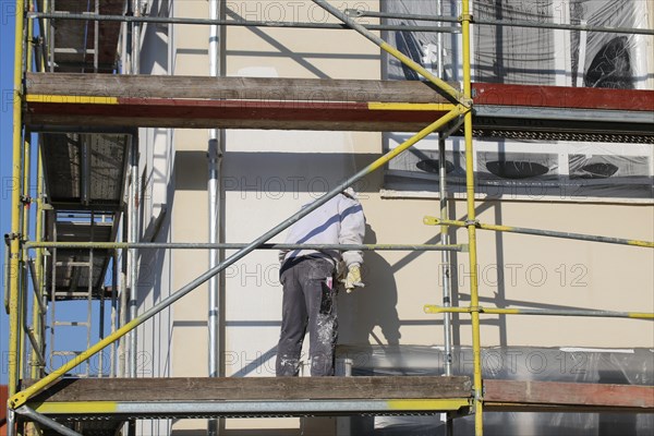 Painter painting the facade of a new residential building (Mutterstadt development area, Rhineland-Palatinate)