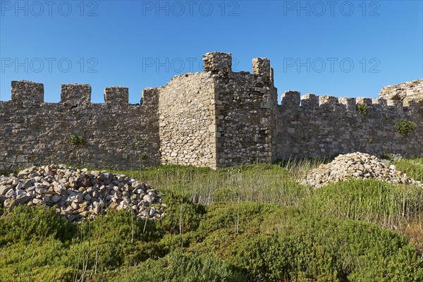 Wide angle shot of a towering castle wall surrounded by greenery with sky in the background, sea fortress Methoni, Peloponnese, Greece, Europe