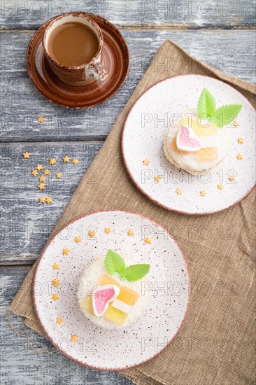 Decorated cake with milk and coconut cream with cup of coffee on a gray wooden background and linen textile. top view, flat lay, close up