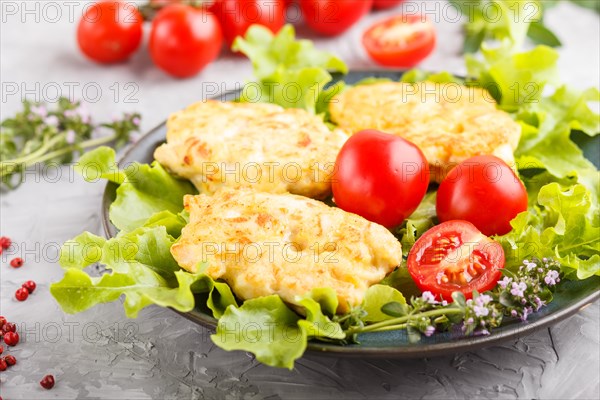 Minced chicken cutlets with lettuce, tomatoes and herbs on a gray concrete background. side view, close up, selective focus