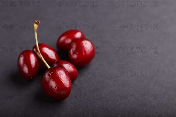 Ugly weird red sweet cherry on black background. side view, close up, copy space, macro, trendy