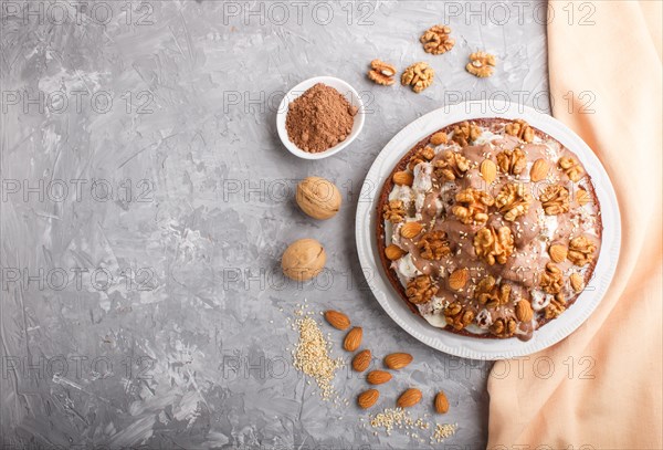 Homemade cake with milk cream, cocoa, almond, hazelnut on a gray concrete background with orange textile. Top view, flat lay, copy space