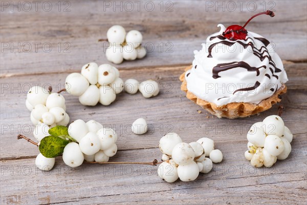 A cake with cream and white berries on a rustic wooden background