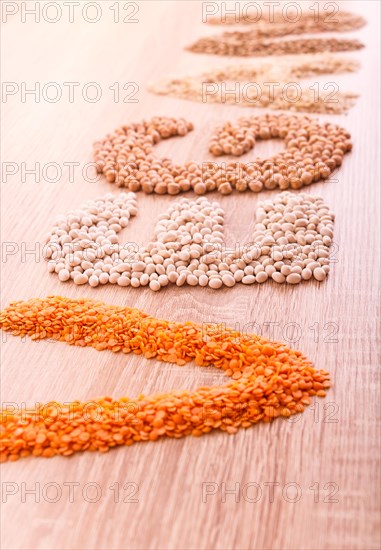 Word Vegan made of lentils, buckwheat, beans, rice and chickpeas on a wooden background