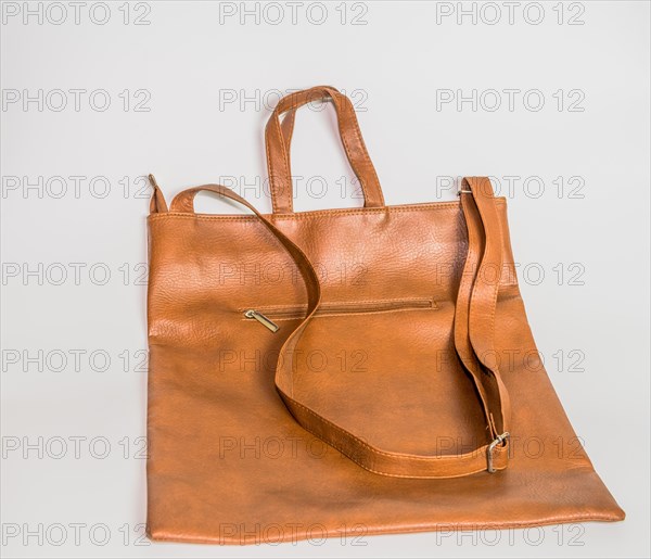 Brown leather shoulder bag with front zipper pocket isolated on white background
