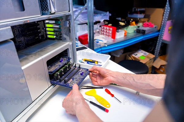 Unrecognizable male technician working on computer conductor board in a repair shop