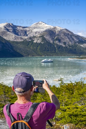 Man photographing the cruise ship Stella Australis in Pia Bay in front of the Pia Glacier, Alberto de Agostini National Park, Avenue of the Glaciers, Chilean Arctic, Patagonia, Chile, South America
