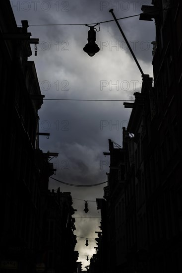 Row of houses with pulleys, architecture, Middle Ages, trade, trading town, warehouse district, facade, city centre, city trip, evening light, silhouette, evening mood, silhouette, lamps, dark, gloomy, mood, dark clouds, Amsterdam, Netherlands