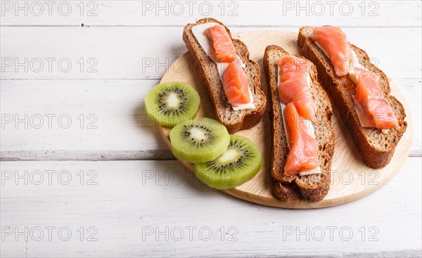 Smoked salmon sandwiches with butter on white wooden background. top view, copy space