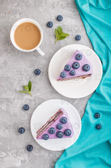Homemade cake with souffle cream and blueberry jam with cup of coffee and fresh blueberries on a gray concrete background. top view, flat lay