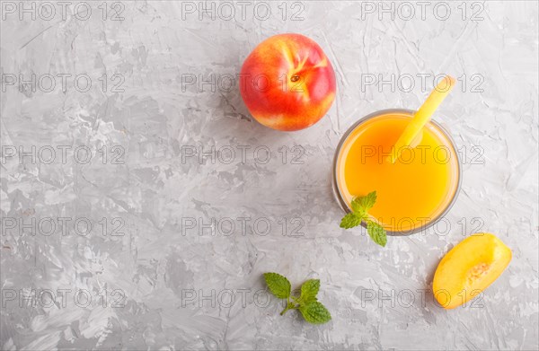 Glass of peach juice on a gray concrete background. Morninig, spring, healthy drink concept. Top view, copy space, flat lay