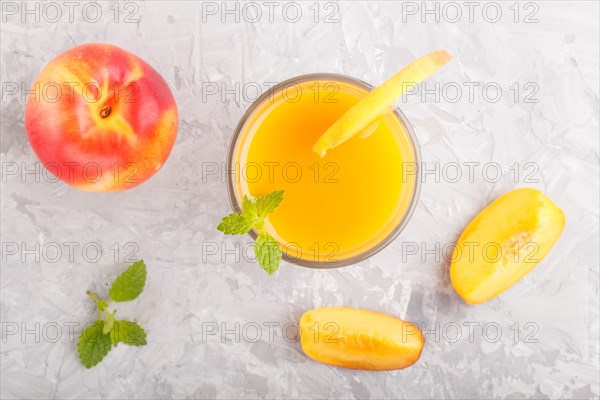 Glass of peach juice on a gray concrete background. Morninig, spring, healthy drink concept. Top view, close up, flat lay