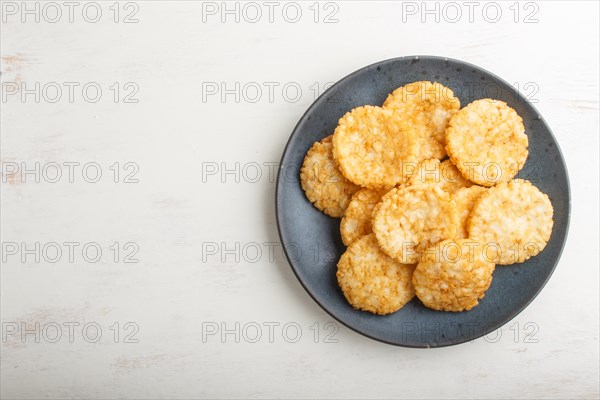 Traditional japanese rice chips cookies with honey and soy sauce on a blue ceramic plate on a white wooden background. Top view, flat lay, copy space
